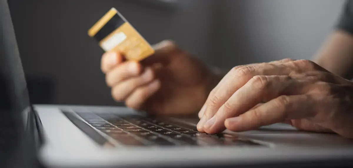 person holding credit card typing on keyboard
